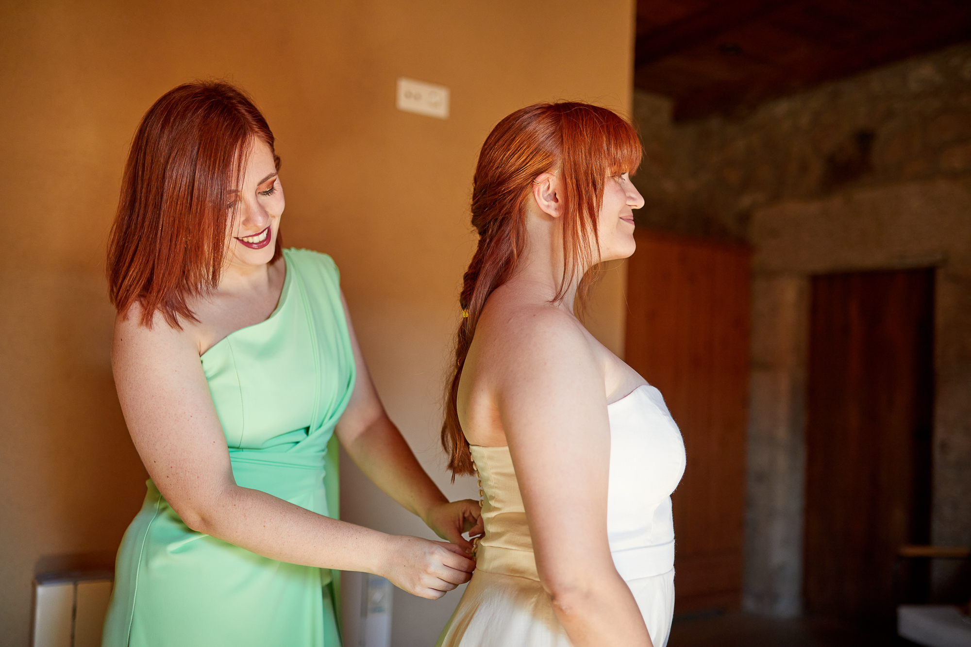 dama de honor ayudando a vestir a la novia